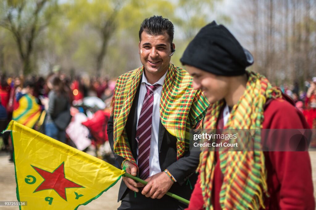TOKYO, JAPAN - MARCH 24:  A Kurdish man holds a flag of the Kurdish People's Protection Units (YPG) as he talks with a friend during Nowruz celebrations on March 24, 2018 in Tokyo, Japan. Nowruz meaning 'new day' and marking the first day of spring, is widely celebrated by Kurdish communities around the world including in Japan where an estimated 2000 Kurds reside, many of whom are claiming refugee status owing to alleged human rights abuses in Turkey and Iraq. Although the Japanese government has issued some temporary permits allowing many to stay for years, no Turkish Kurd has ever been received refugee status in Japan, which would allow them to settle permanently.æ (Photo by Carl Court/Getty Images)